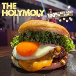 Bild von The HolyMoly Burger mit Dry Aged Steak Patty, Spiegelei, Cheddar, Gurkenrelish, Tomatensalsa, Salat und einem Brioche Bun bei HolyMoly Burger & Bar Neuwied